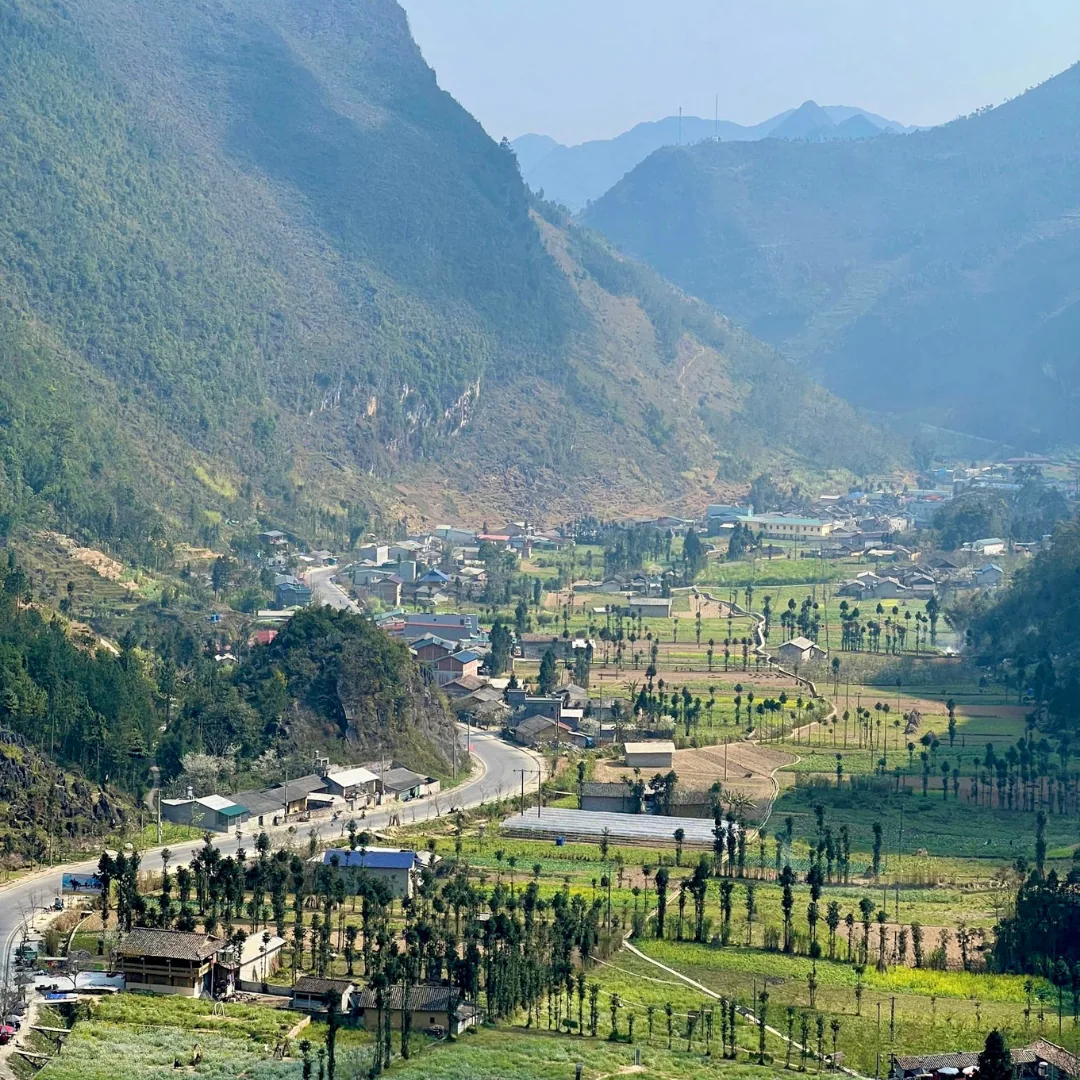 A valley town on the main road into Ha Giang, houses and cultivated fields on the valley floor with steep limestone ridges rising on both sides